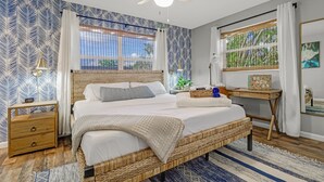 Une chambre avec un grand lit, une table de chevet en bois, un bureau et une fenêtre donnant sur un paysage verdoyant.