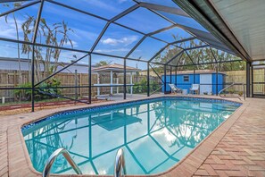 A clear pool with a glass enclosure, surrounded by a wooden deck and a fenced backyard. - Modern Pool Home • Central Fort Myers Location (Fort Myers)