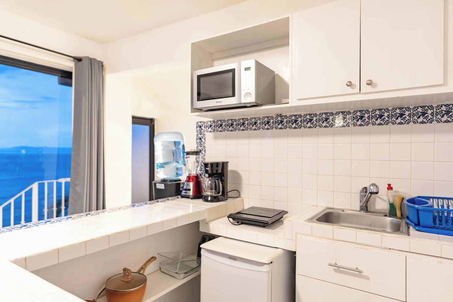 Una cucina con microonde, macchina del caffè e vista sul mare.