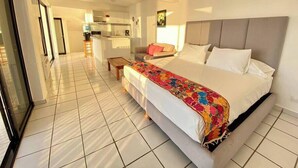 A hotel room with a large bed, a small table, and a kitchenette in the background. - Condo 1 at Del Mar PV (Aguacate)