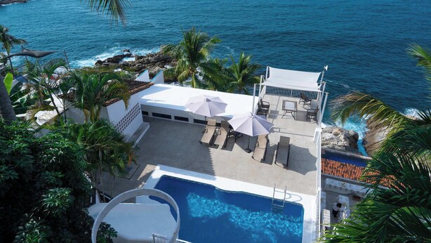A rooftop pool area with lounge chairs and umbrellas, overlooking a body of water. - Condo 1 at Del Mar PV (Aguacate)