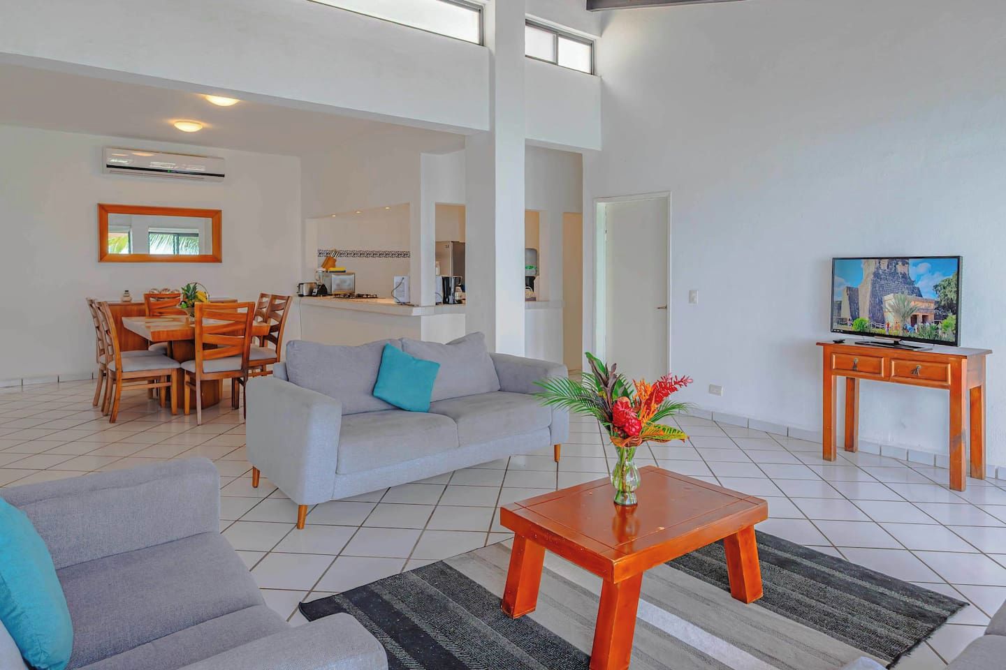 A modern living room with a grey sofa, a coffee table, and a TV on a wooden stand.