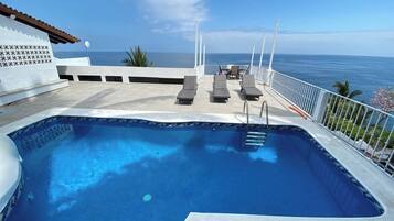 Ein Pool mit Liegestühlen und Blick aufs Meer.
