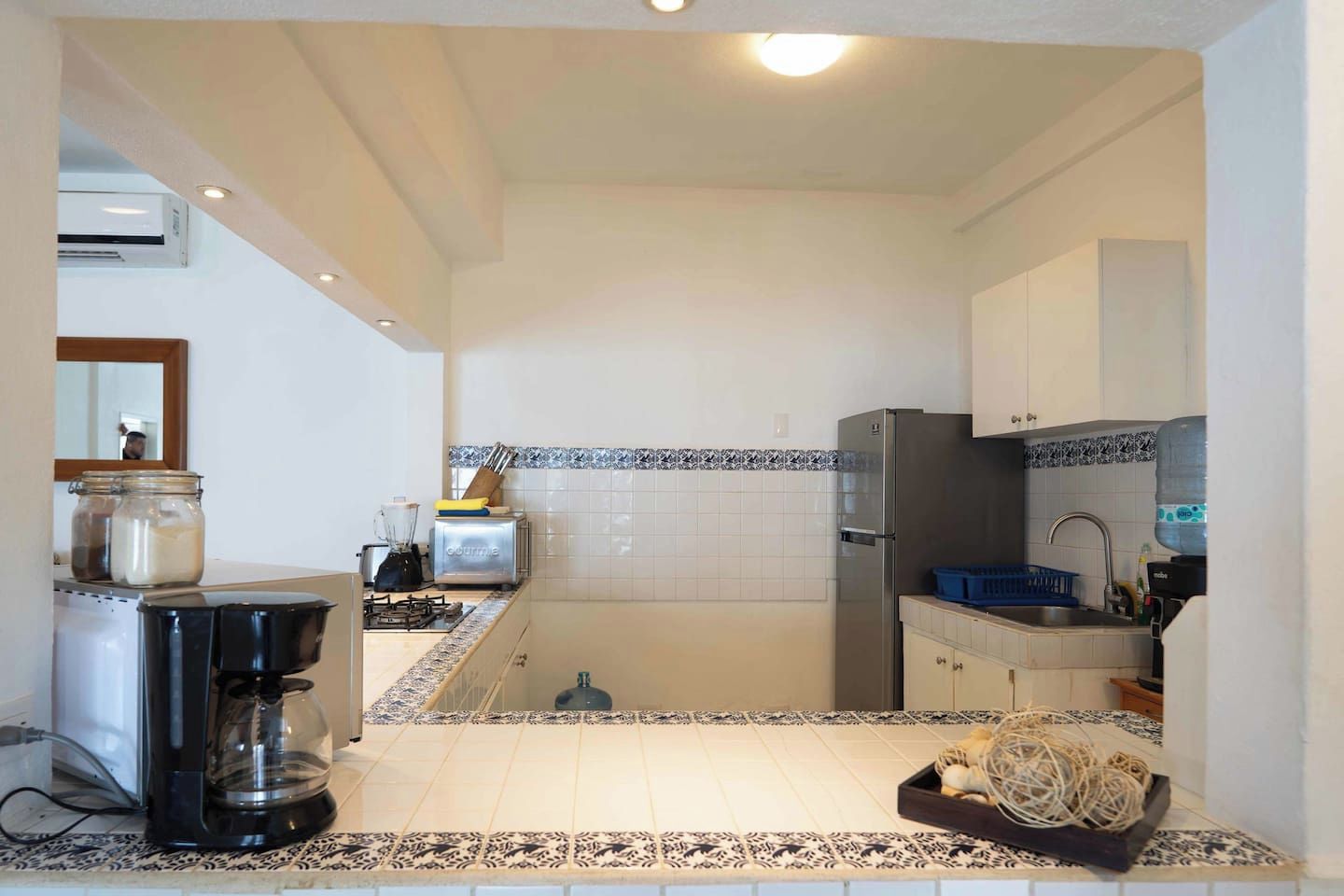 Eine kleine Küche mit Gaskochfeld, Kaffeemaschine und Kühlschrank.