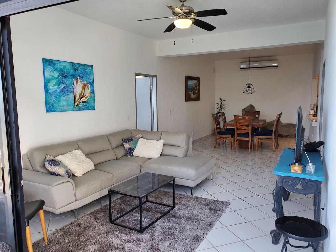 A living room with a sofa, coffee table, and a dining area with chairs and a table.