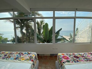 A room with two beds, large windows, and a view of the sea and palm trees. - Oceanfront Villa: Private Resort w/ Heated Pools (Aguacate)