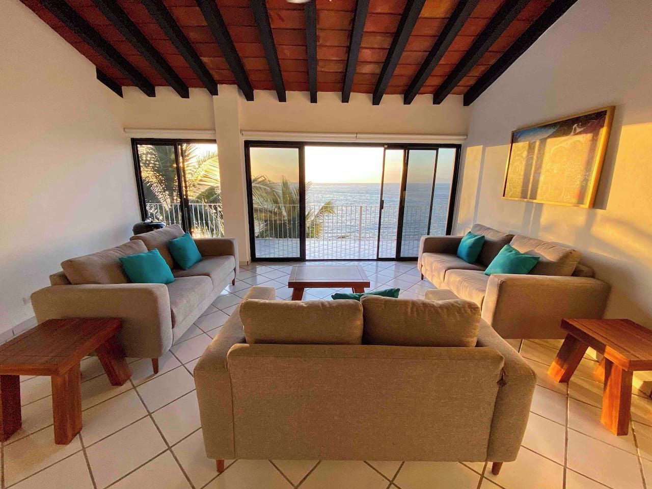 Sala de estar com dois sofás, uma mesa de centro e vista para o oceano através de grandes portas de vidro.