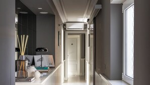 A narrow hallway with a white radiator, a window on the right, and a door at the end. - Naman Hotellerie - Spagna (Rome)