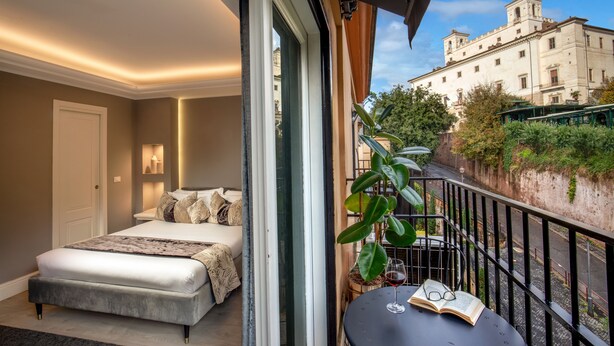 A bedroom with a bed, bedside table, and a balcony with a view of a building. - Naman Hotellerie - Spagna (Rome)