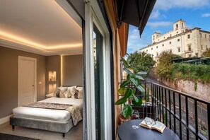 A bedroom with a bed, bedside table, and a balcony with a view of a building. - Naman Hotellerie - Spagna (Rome)