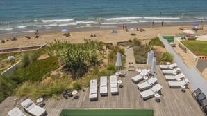 Un resort frente a la playa con sillones de sol, piscina y vista al océano.