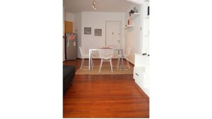 A dining area with a table and chairs, a refrigerator, and a white door in the background.