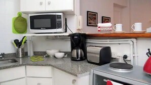 A kitchen with a microwave, coffee maker, toaster, and a sink.