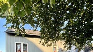 Un bâtiment à deux étages avec une façade en pierre, un banc rouge et des plantes en pot dans le hall d'entrée.
