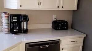 A kitchen with white cabinets, a coffee maker, a toaster, and a dishwasher. - Peoria Corner Lot 3 Bedroom 2 Bath with High Speed Internet/Smart TVs (Peoria)