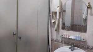 Une salle de bain avec une douche à parois de verre, un lavabo blanc et un miroir au-dessus du lavabo.