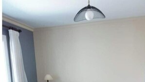 Un dormitorio con cama, mesita de noche, lámpara, ventana con cortinas y cómoda de madera.