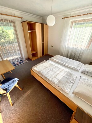 Ein Schlafzimmer mit einem großen Bett, einem Holzschrank, einem kleinen Tisch und einem Stuhl.