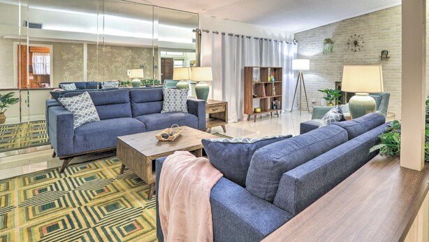 A modern living room with a sofa set, a coffee table, and a bookshelf. - Retro St Pete Home w/ Private Heated Pool (St. Petersburg)