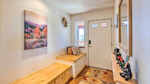 Un couloir avec un banc, un tableau, une porte et une étagère où sont exposées des figurines.