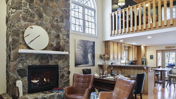 A spacious living area with a stone fireplace, leather chairs, and a high ceiling with wooden beams. - Acorn Ridge: Modern Shenandoah Mountain 4 Bedroom 4 Bathroom, Firepit, Theater (Basye)
