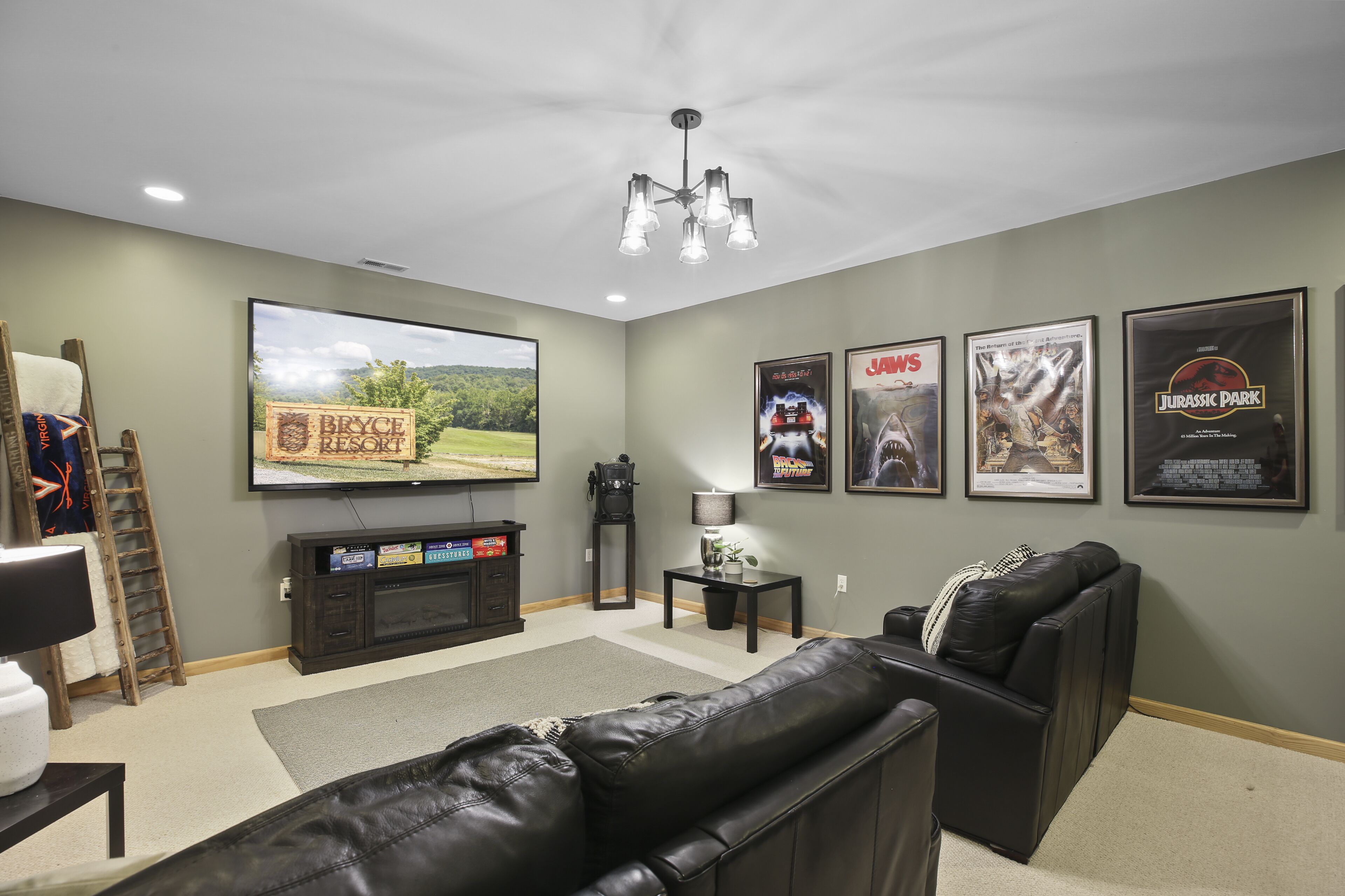 Una sala de estar con televisor de pantalla plana, chimenea, sofá y carteles de películas enmarcados en la pared.