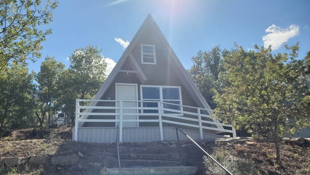 A small, triangular-shaped cabin with a white railing and a single door. - Modern Relaxing Lakeside Cabin #3 (Cisco)