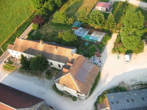 An aerial view of a rural property with a large house, a greenhouse, and a small building with a red roof.