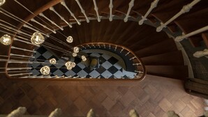 En trappe i træ, formet som en spiral, med et skakternet gulv og hængende, kugleformede lysarmaturer.