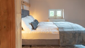 Et soveværelse med seng, puder, et vindue og en radiator.
