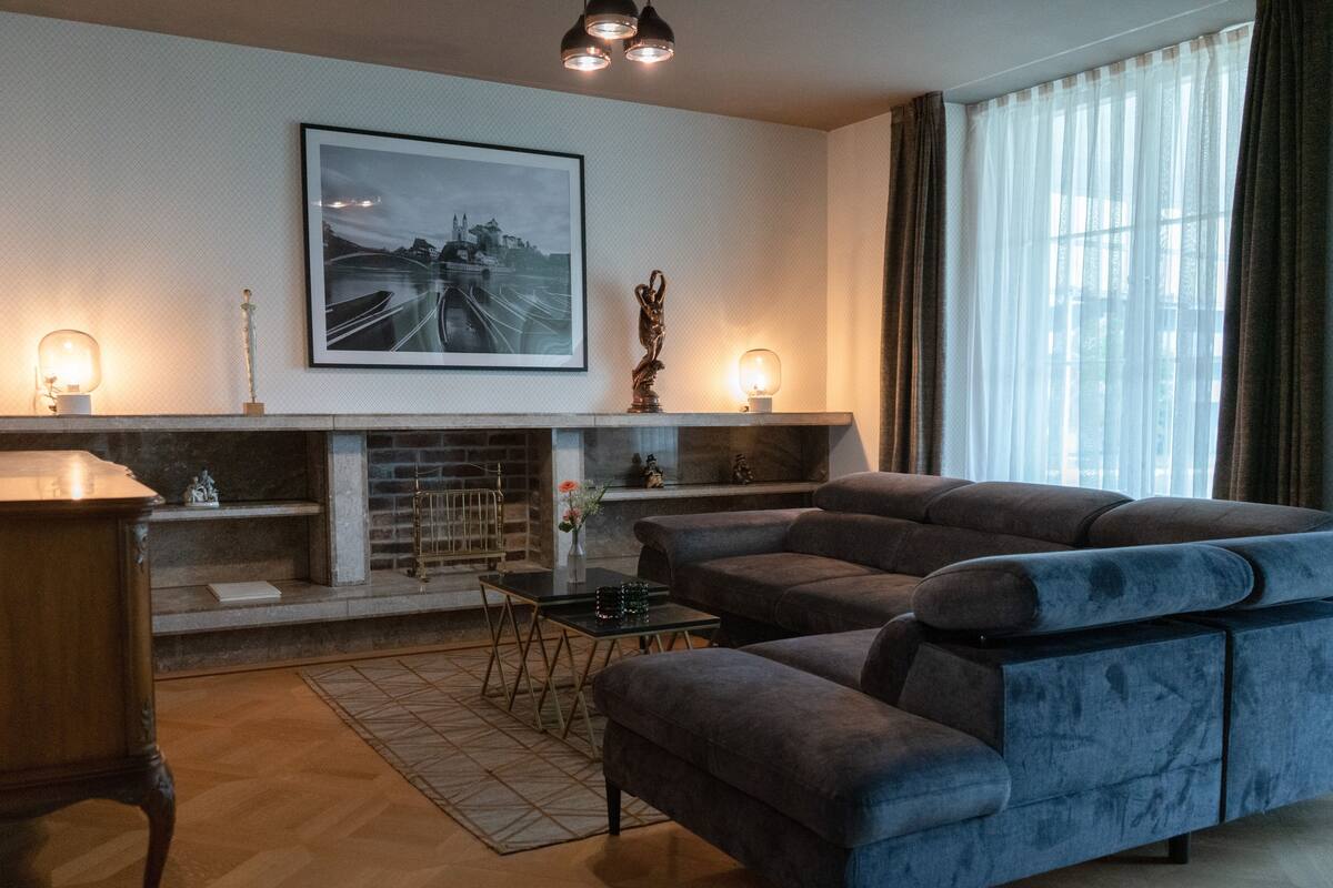A modern living room with a sectional sofa, a fireplace, and a large framed picture on the wall.