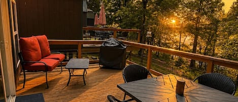 A wooden deck with outdoor furniture, including a table and chairs, and a red sofa.