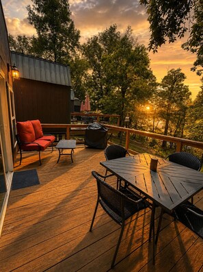 A wooden deck with outdoor furniture, including a table and chairs, and a red sofa.