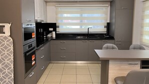 A compact kitchen with a built-in oven, a sink, and a window with blinds. - Quiet escape, good security and serene environment (Accra)