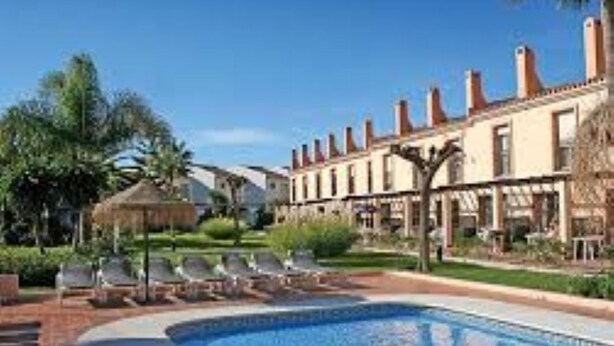 A swimming pool with lounge chairs and a building with multiple chimneys. - NEW LAUNCH!!! Wyndham Beach and Pools Resort in La Cala, Mijas & Fuengirola (Las Lagunas de Mijas)