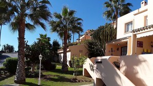 A courtyard with palm trees, a pathway, and a building with a tiled roof. - NEW LAUNCH!!! Wyndham Beach and Pools Resort in La Cala, Mijas & Fuengirola (Las Lagunas de Mijas)