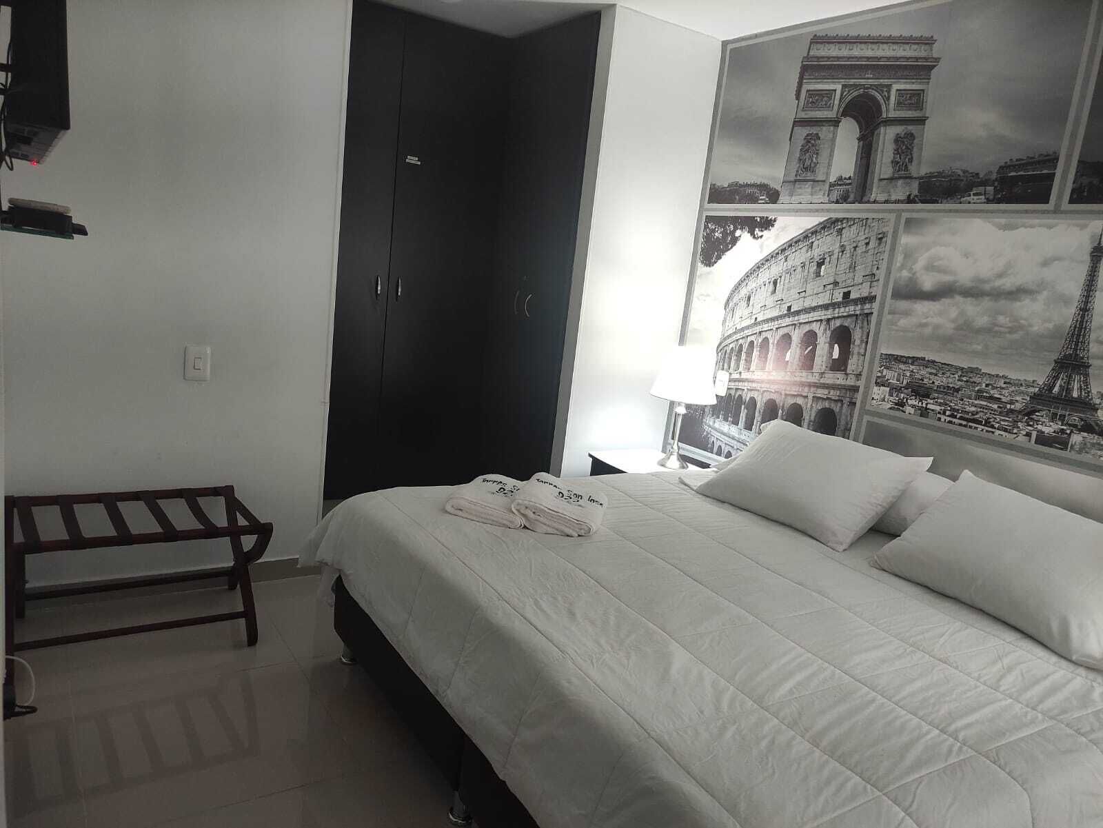 Ein Hotelzimmer mit einem Bett, einem Kleiderschrank und einer Wand mit einer Collage berühmter Sehenswürdigkeiten.