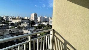 Ein Balkon mit Blick auf eine Stadtlandschaft, darunter Gebäude und Bäume.