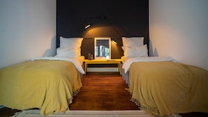 Una camera da letto con due letti, un tavolino e una lampada.
