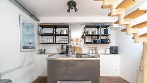Una cucina compatta con un'isola centrale, scaffali neri e una scala in legno.