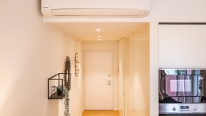 A hallway with a white door, a mounted air conditioner, and a wall-mounted TV.