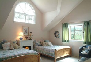 A bedroom with two wooden beds, a fireplace, a large arched window, and a view of greenery outside. - Countryside home with expansive views of the hills and valleys of Julian. (Julian)