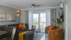 Een moderne woonkamer met een grijze bank, een bruine fauteuil, een salontafel en een plafondventilator.