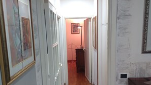 A hallway with wooden flooring, white walls, and multiple framed pictures. - One step away (Arezzo)