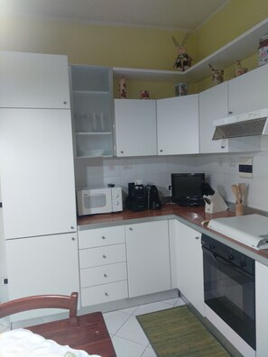 A compact kitchen with white cabinets, a microwave, a coffee maker, and a toaster. - One step away (Arezzo)