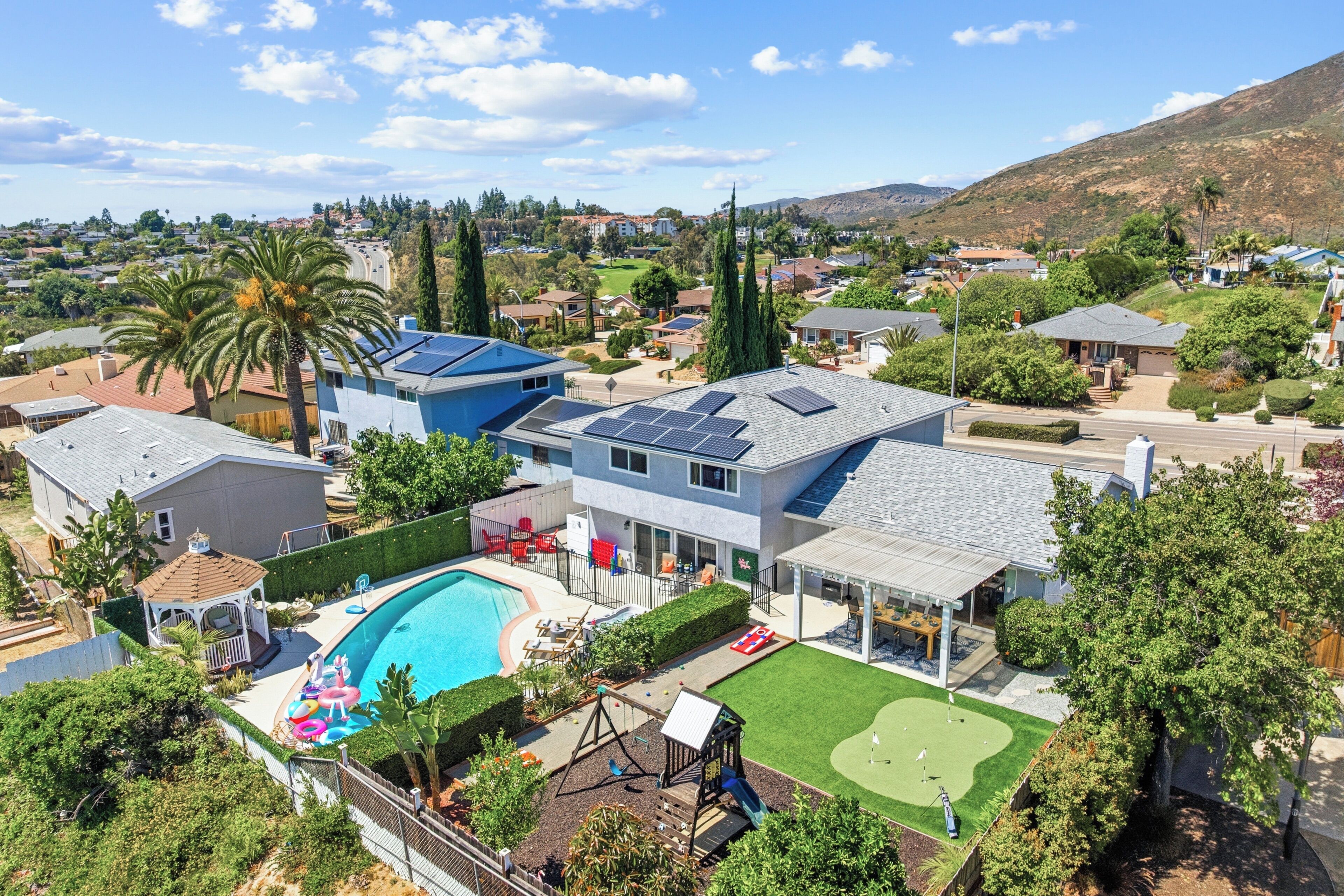 A residential area with a swimming pool, solar panels, and a well-maintained lawn.