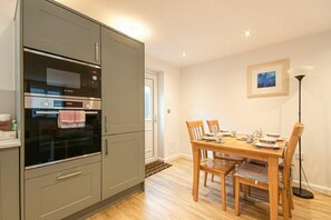A kitchen with a Bosch oven, a dining table with chairs, and a framed picture on the wall.