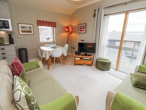 A cozy living room with a dining area, a television, and a view of the outside.