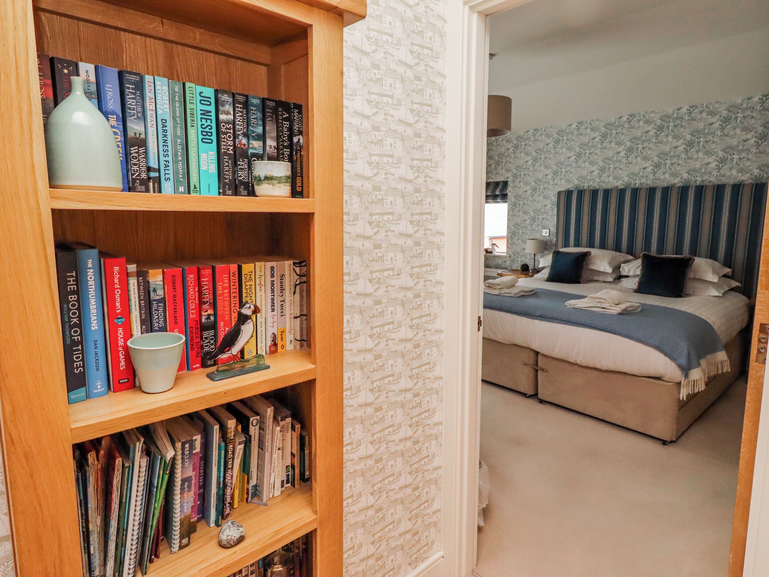 Un dormitorio con una cama, una mesita de noche y una estantería llena de libros.