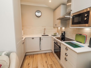 A compact kitchen with white cabinets, a stainless steel oven, a microwave, and a coffee maker.